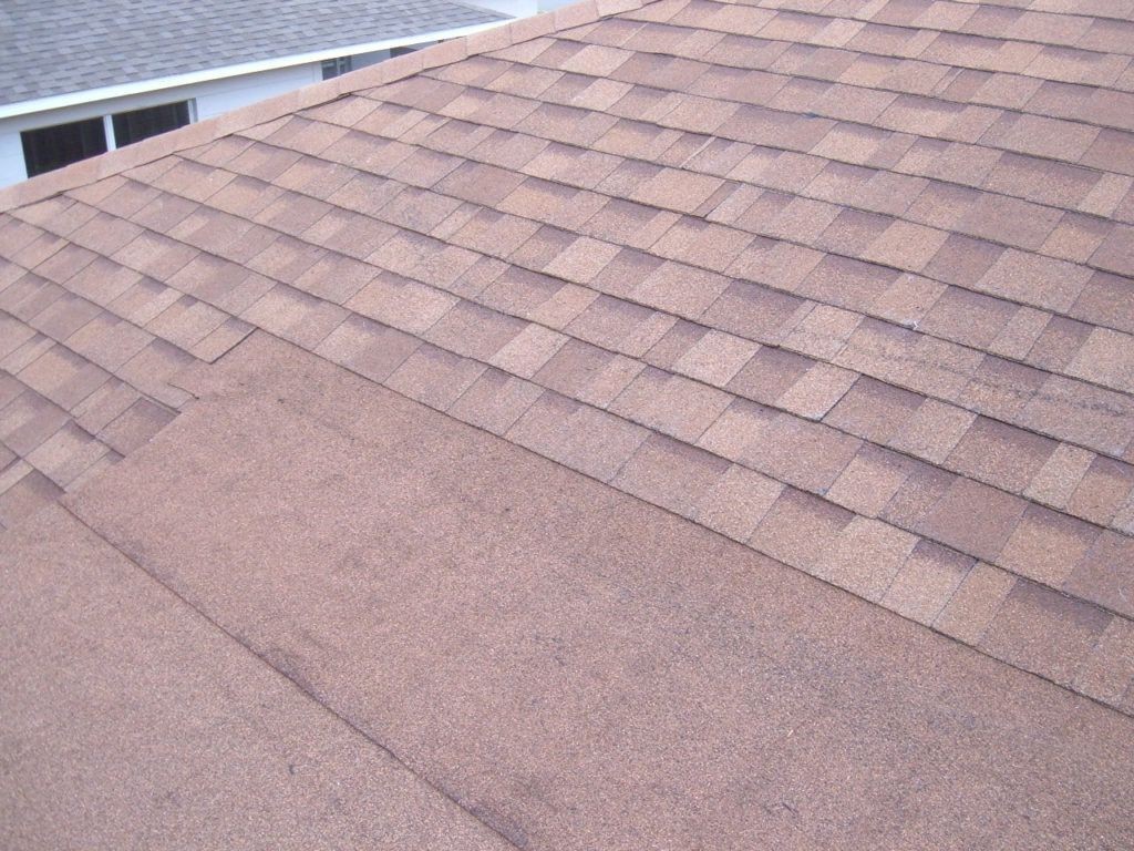 Close-up view of a residential roof with newly installed brown asphalt shingles.